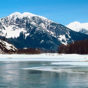 The Skeena River flows beneath snow-capped mountains.