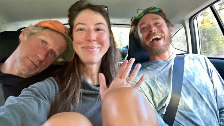 Three hikers celebrate in a car.