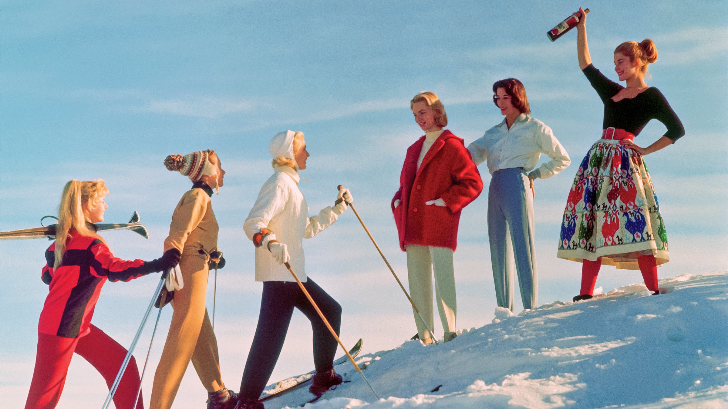 A group of ladies welcome their friends back from a day's skiing, with an apres ski drink.