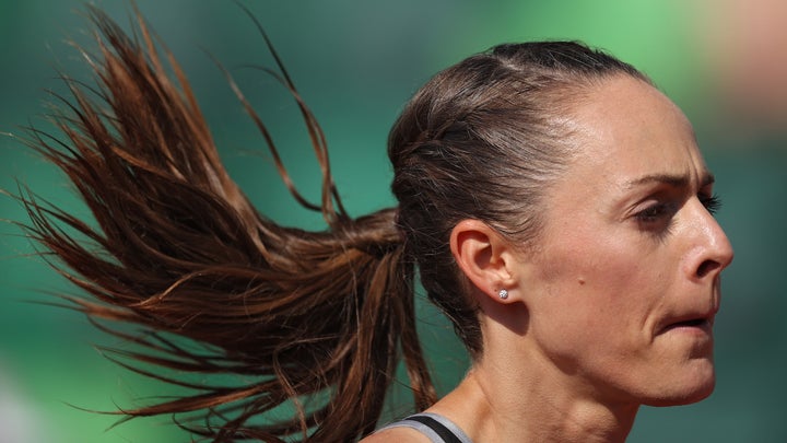 A woman runs with brown hair and a green background
