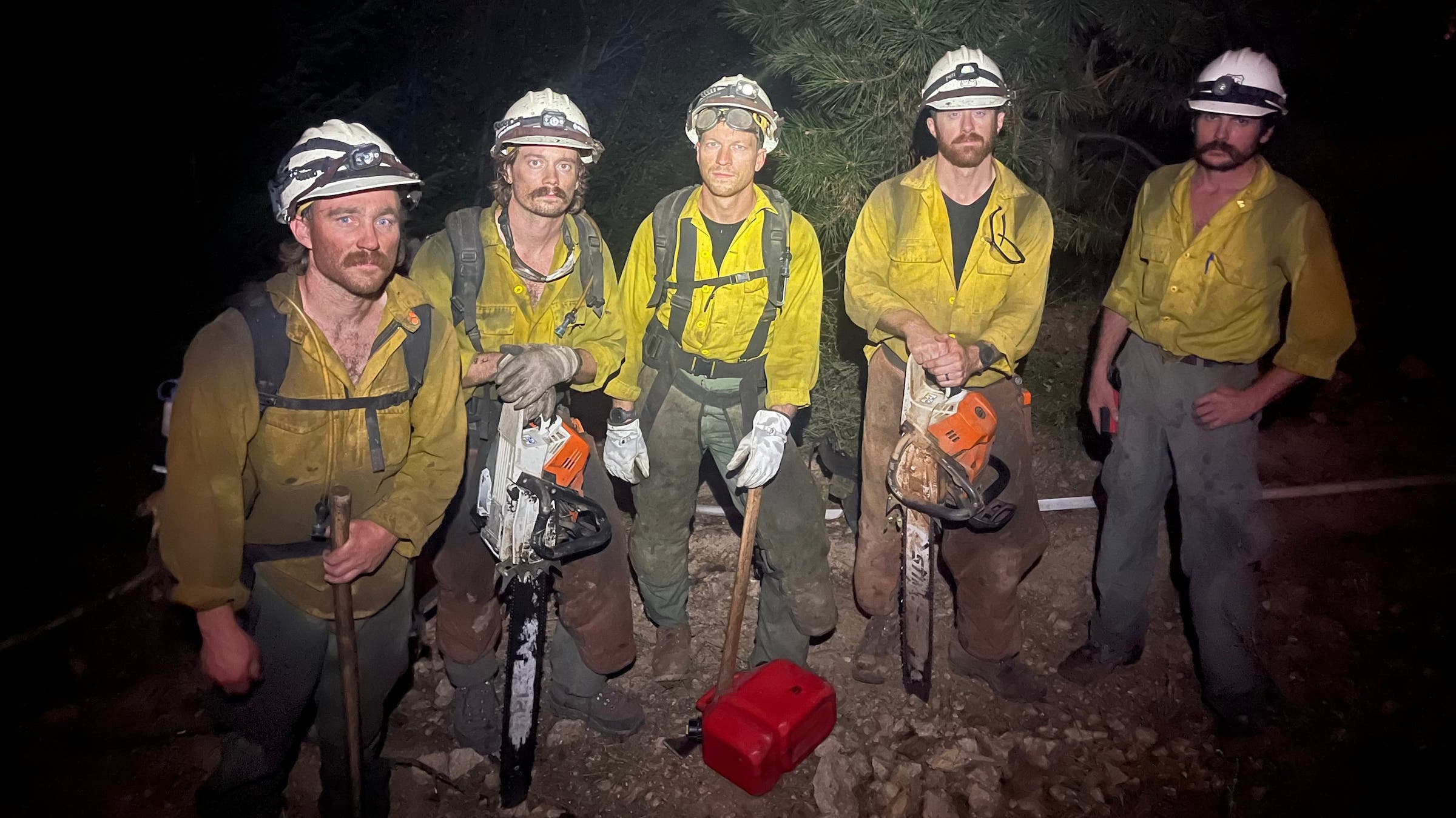 A group of firefighting men at night in yellow.