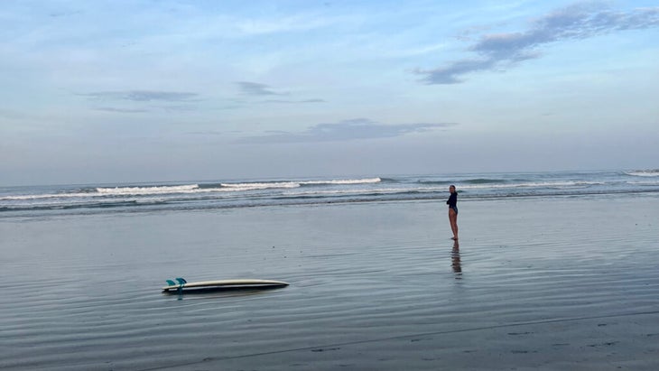 girl walking the shore of Nosara with her surfboard nearby