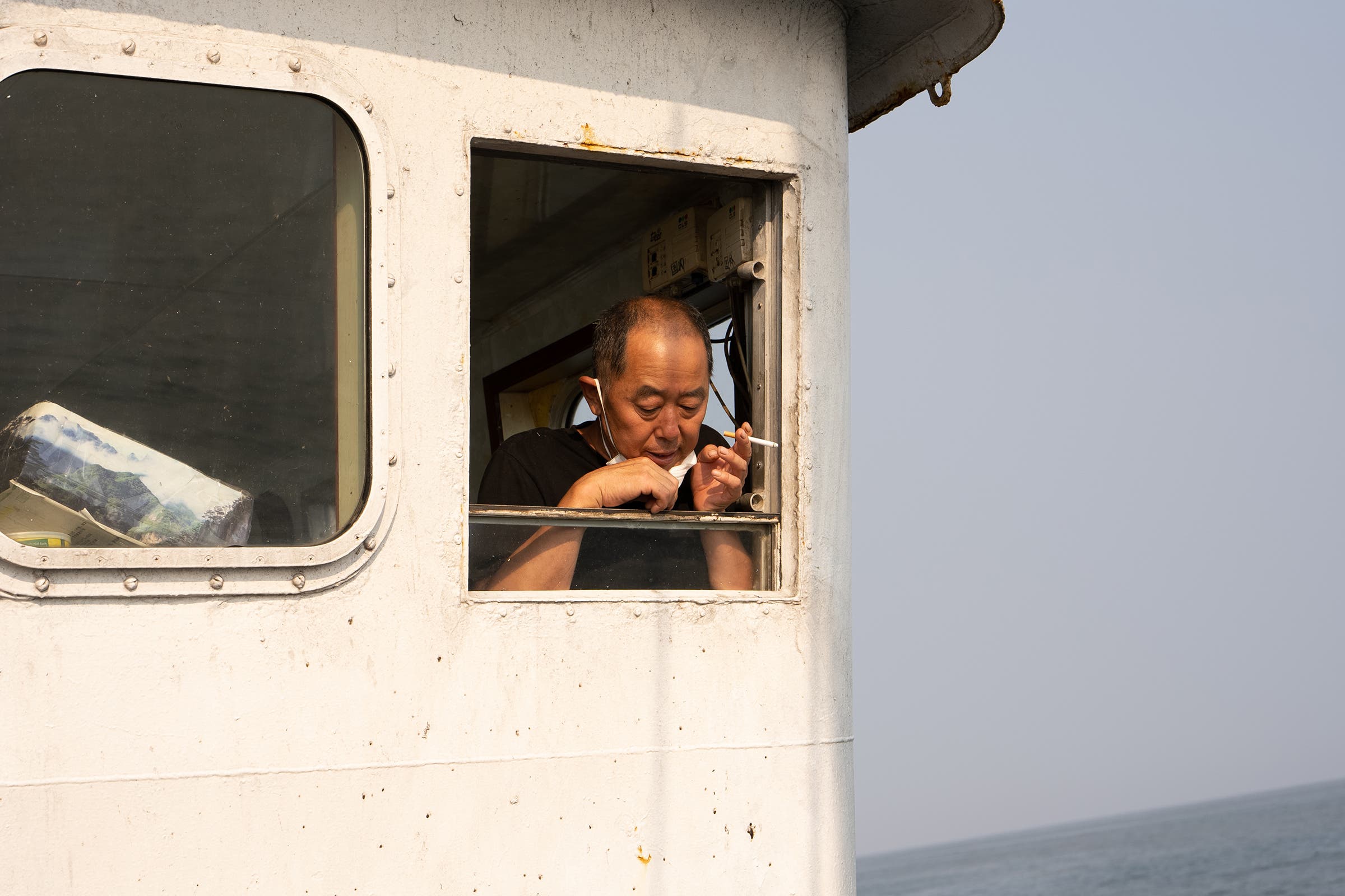 The captain of Guo Ji 827 smokes out the bridge window