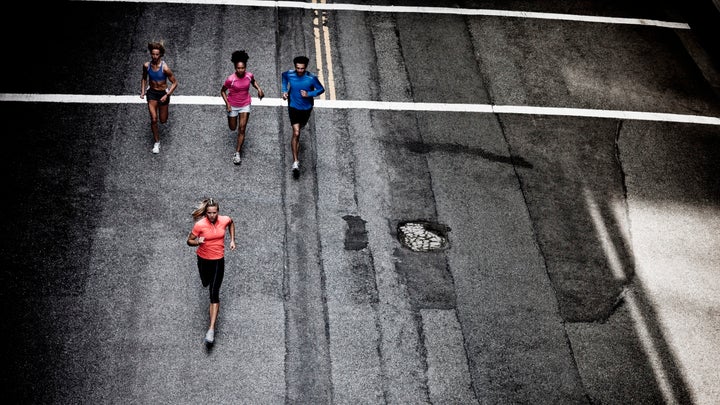 Four people running down a dark road.