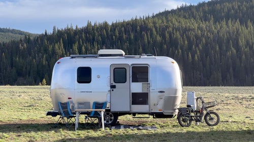 Airstream parked off-grid in field with camp setup.