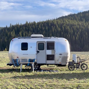 Airstream parked off-grid in field with camp setup.
