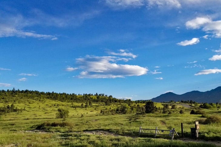 Trailhead with hikes leading up hills and a blue sky.