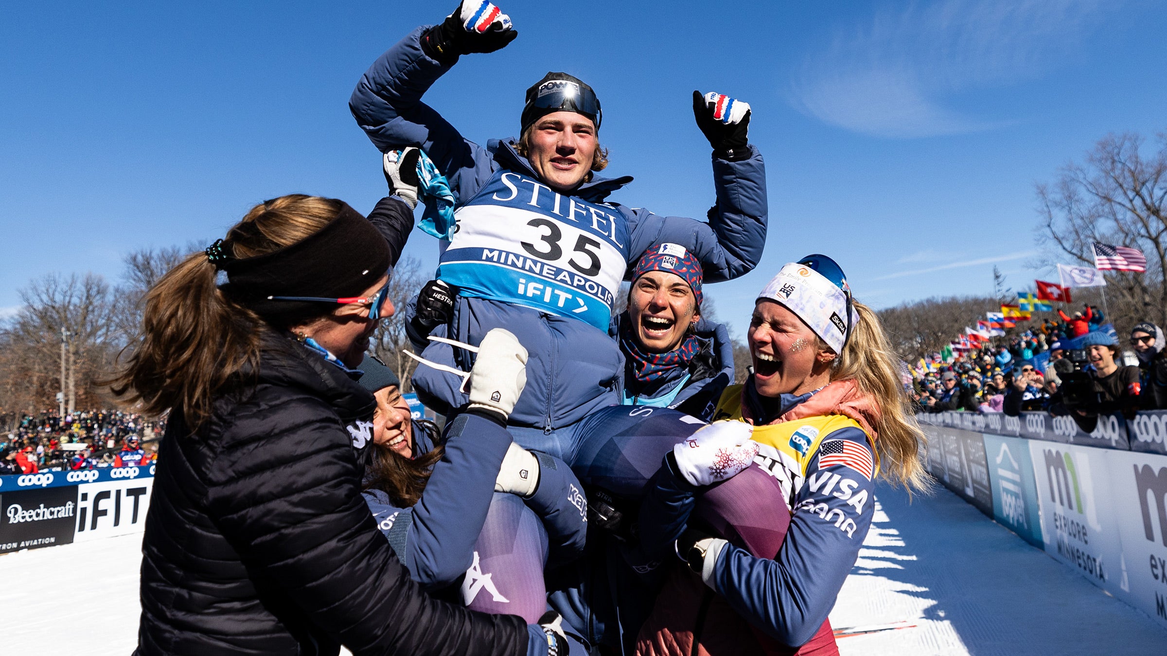 A young skier is held into the air after winning a race.