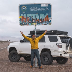 Creator Jacob Moon in front of the Welcome to Nevada sign on a Southern Nevada road trip