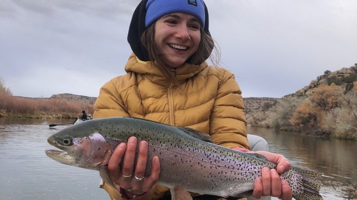 Senior editor Abigail Barronian holds a large rainbow trout that she hooked from New Mexico’s San Juan River.
