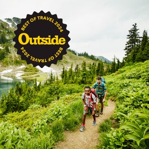 Father and son hiking on mountain trail near alpine lake during backpacking trip