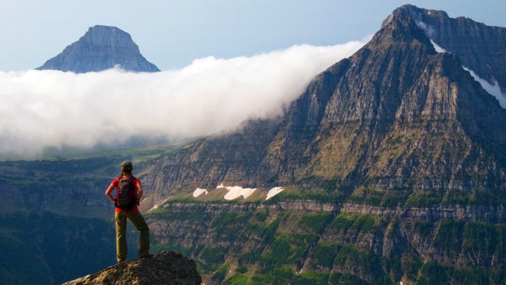 A female hiker takes in the view of Glacier National Park, Montana, from the Highline Trail.