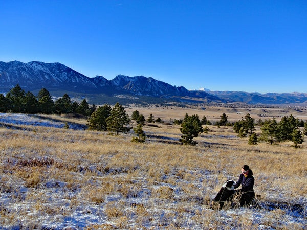 Woman and dog in front of mountains at Marshall Mesa in Boulder, Colorado