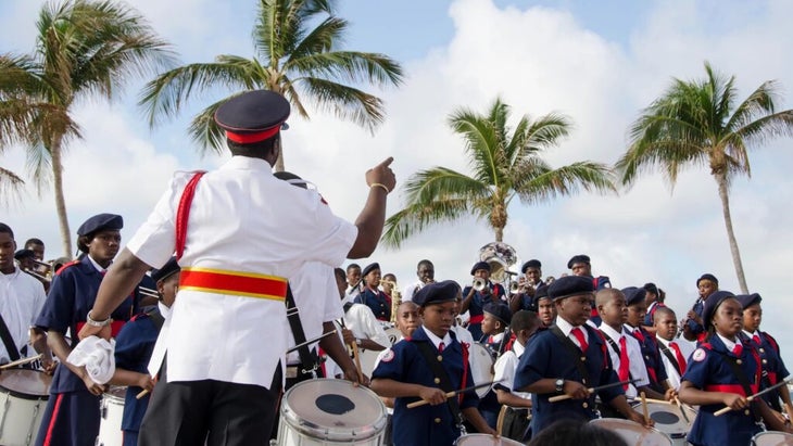 A youth band, headed by a conductor wearing a white jacket and hat, prepare to perform on the streets of Nassau, Bahamas.