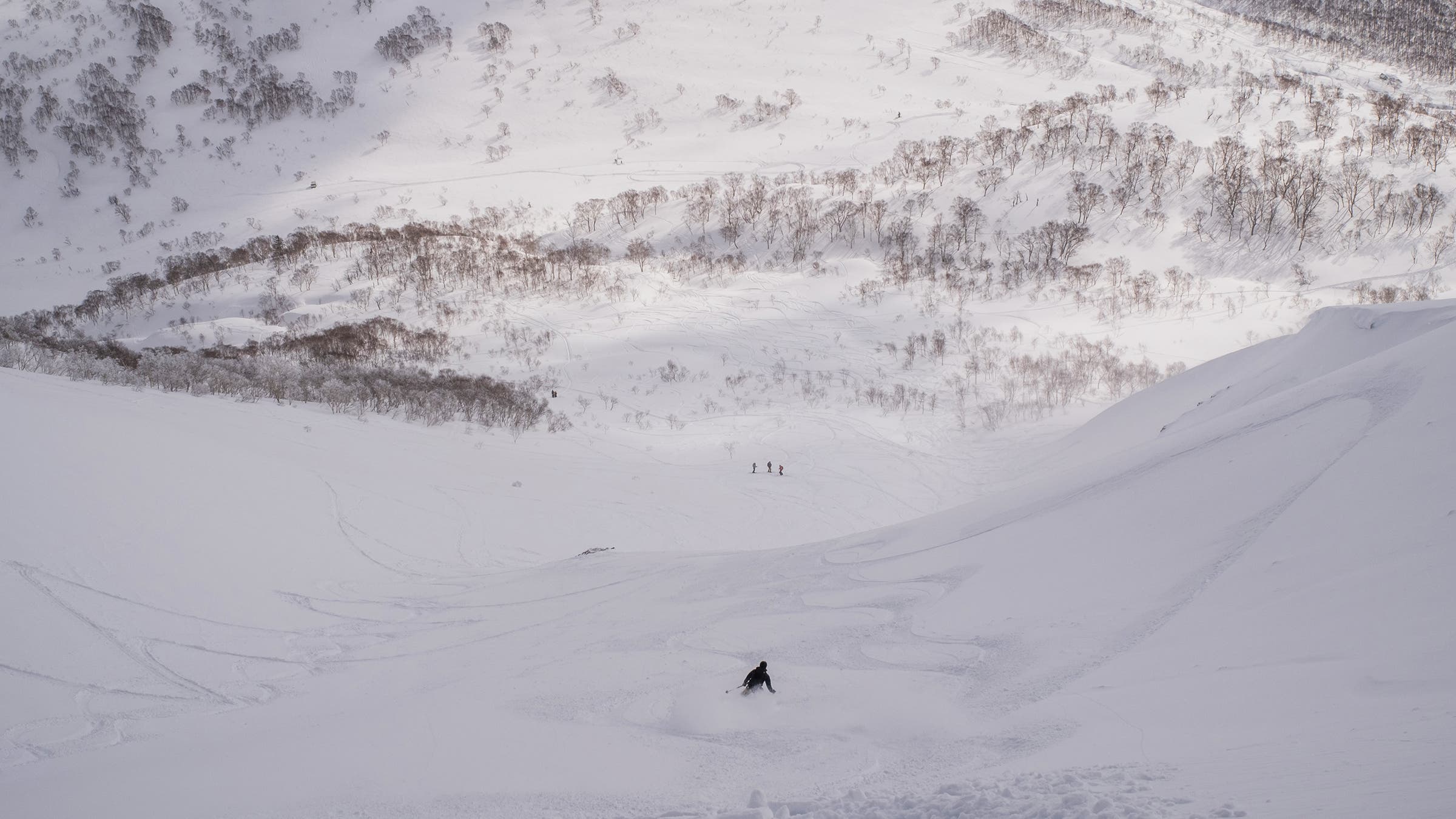 A visitor enjoys the powder after exiting a side-country gate at the top of Niseko United, Japan.