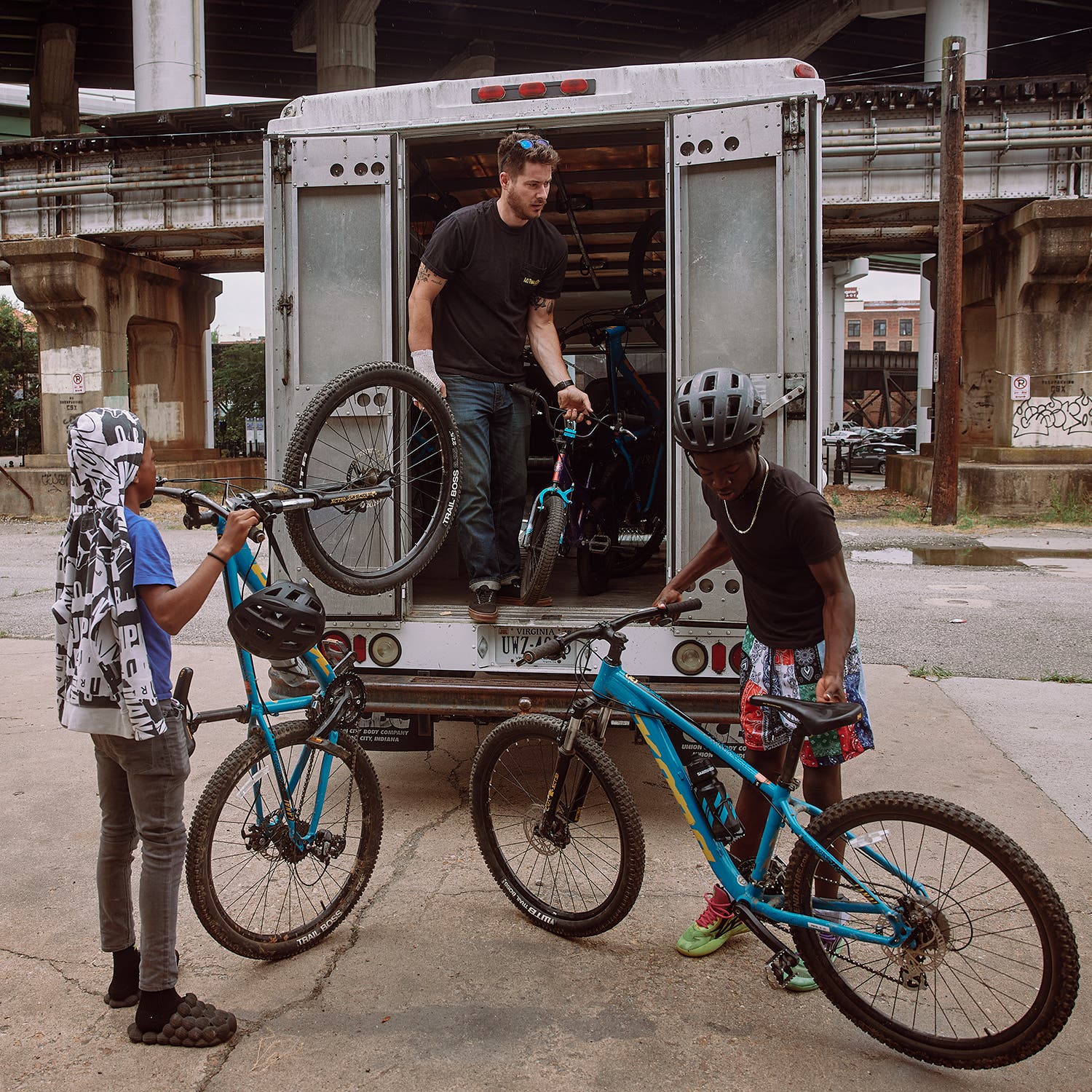 Richmond Cycling Corps coach and executive director Matt Kuhn loads bikes with Malachi Dewitt (left) and Tavon Baskerville at the group’s headquarters prior to a group ride.