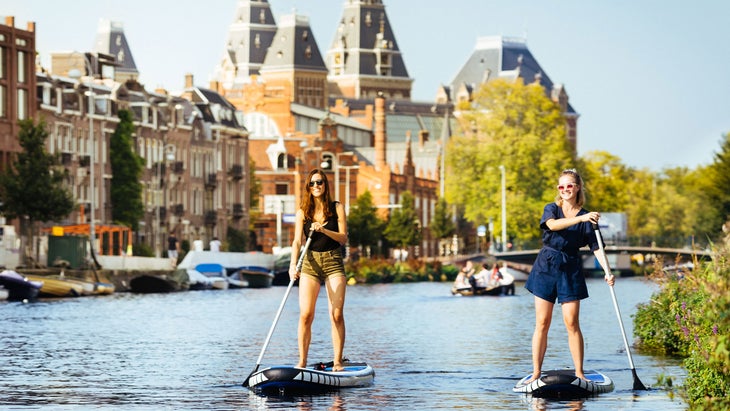 two women standup paddleboarding on Amsterdam canals