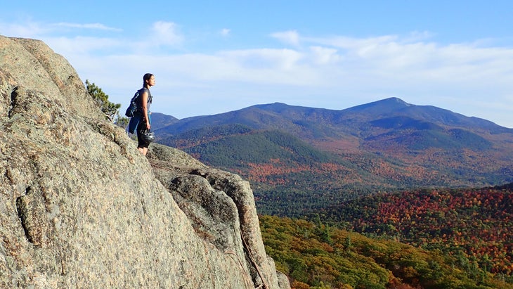 young woman standing on clifftop in Adirondacks