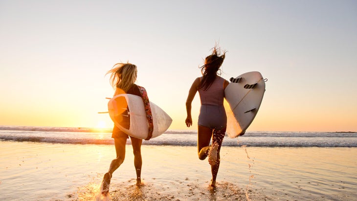 Women surfers running for the water in La Jolla, California