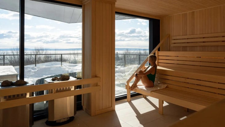 A woman sits in the sauna at Club Med Quebec Charlevoix in Canada, looking out at the Saint Lawrence River.