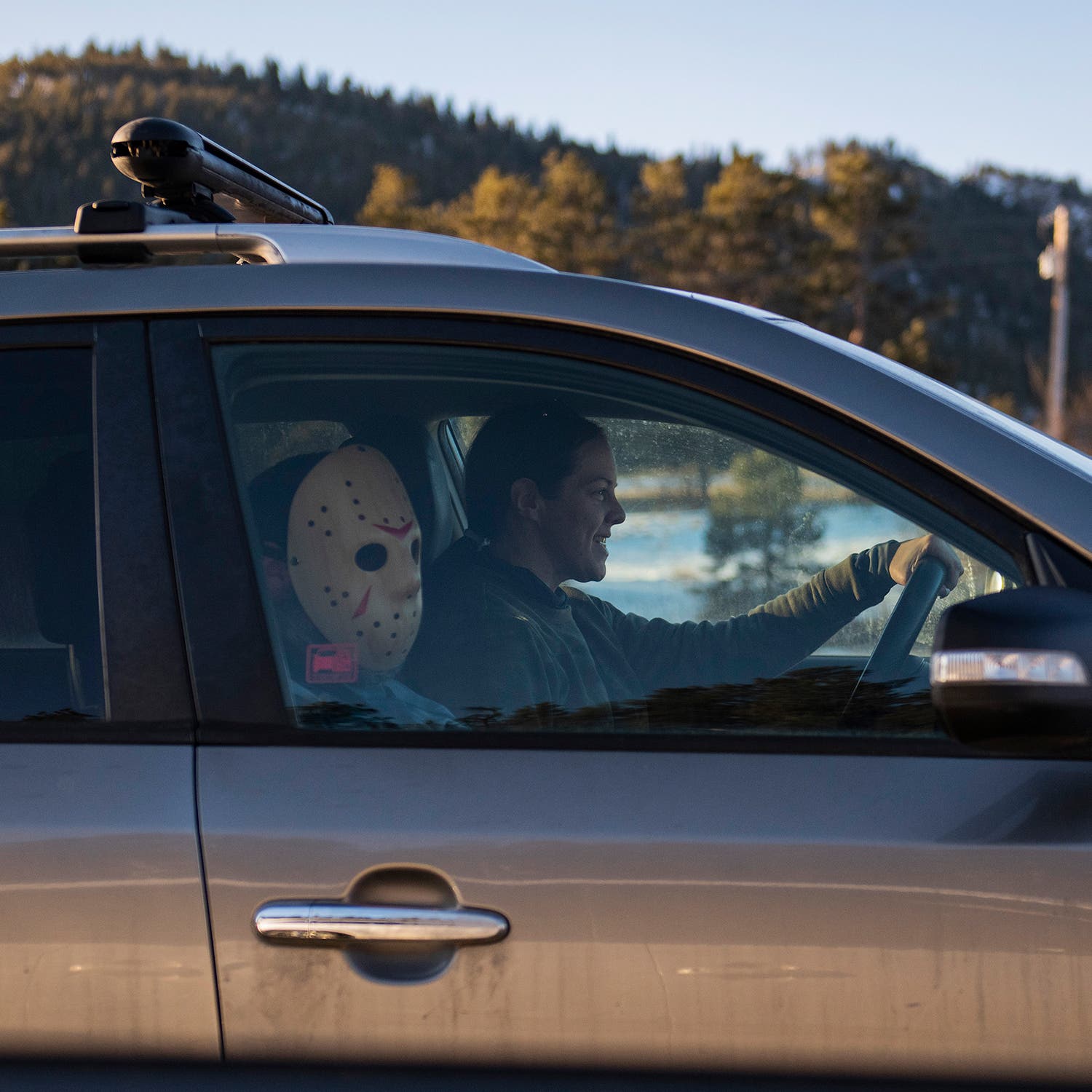 Two passengers, one of them wearing a costume mask, drive west Saturday, January 6, on I-70 in Colorado.