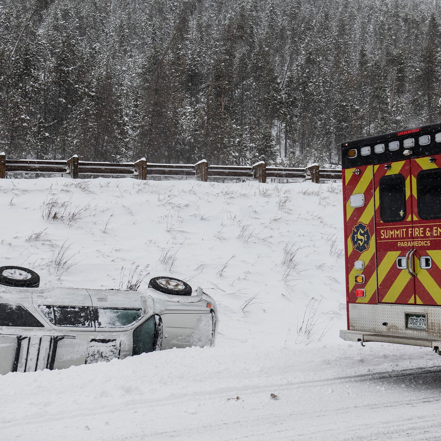A vehicle is seen on its side, off the road, while emergency services arrive on Sunday, January 14, on Interstate 70 in Summit County, Colorado.