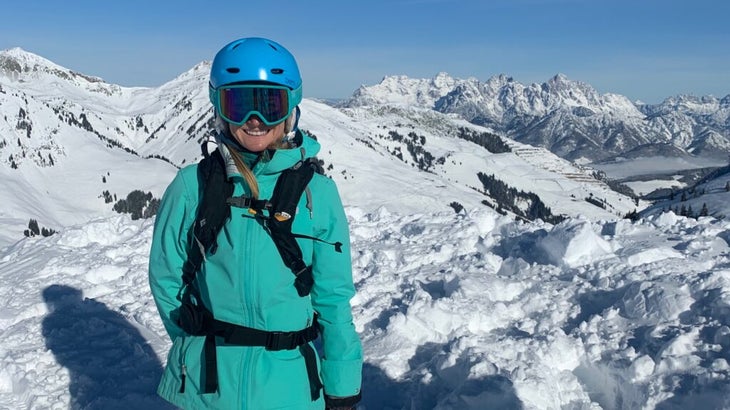 The author wearing ski gear and a helmet atop a stunning alpine-scape in Hinterglemm, Austria.