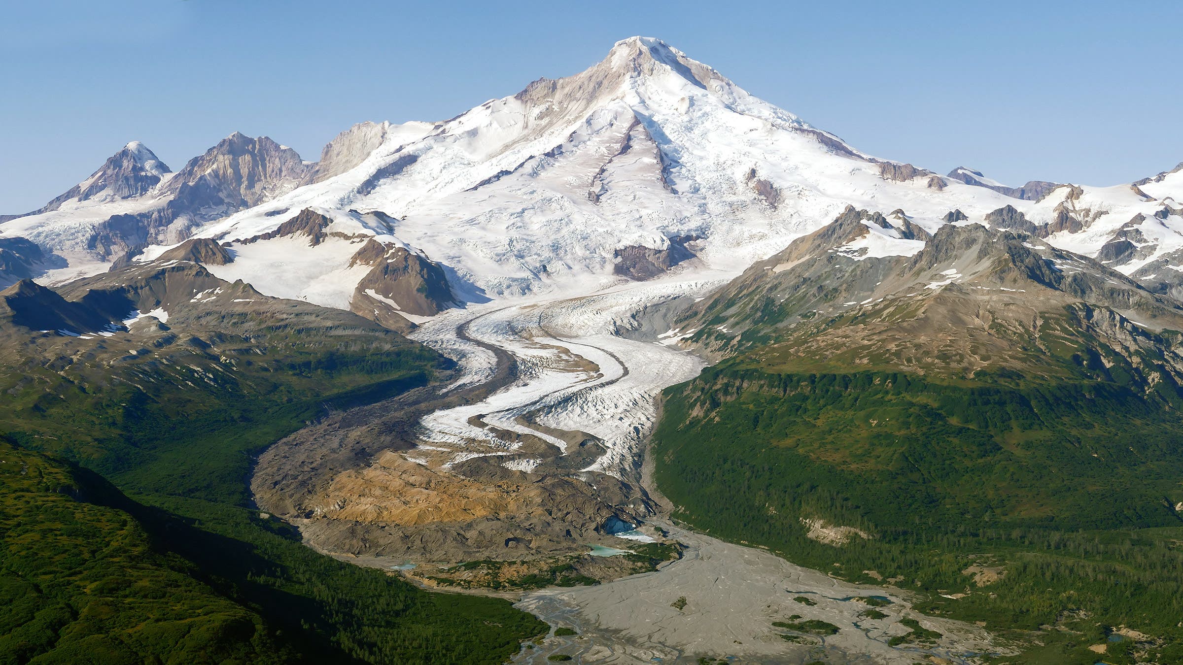 glacier in Lake Clark National Park A glacier flows out from Iliamna Volcano towards a broad outwash plain along the Johnson River in this aerial photo en route to Silver Salmon Creek.