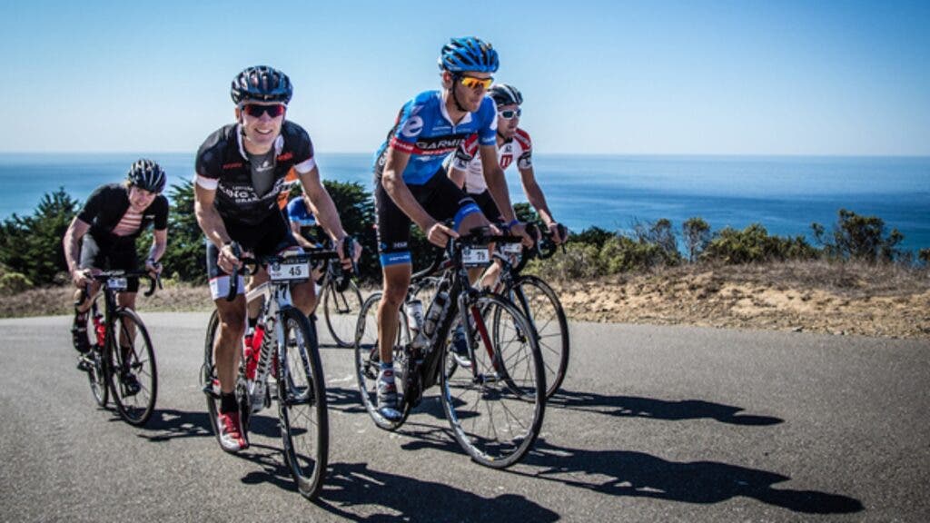 A group of riders follow pro cyclist Pete Stetina, wearing a blue kit and helmet, up a hill in Sonoma County.