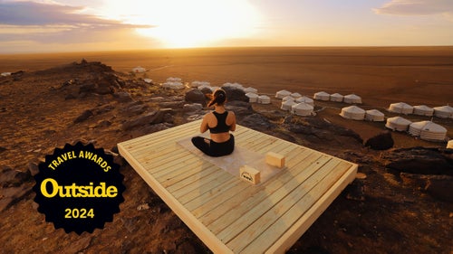 A woman on a yoga platform starts her dawn practice at Mongolia’s Three Camel Lodge.