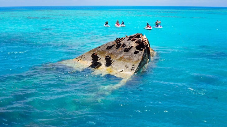 A group of jet skiers circle a shipwreck in the turquoise waters of the coast of Bermuda. 