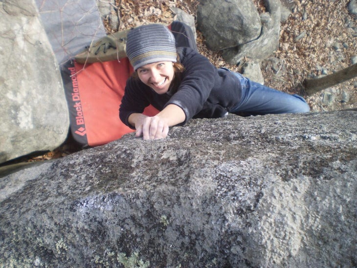 A top-down photo of a climber at the Asheboro Boulders, smiling as she nears the top of a climb.