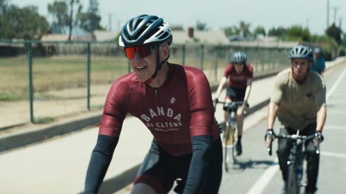 Actor Matthew Modine pedals a road bicycle alongside other cyclists.
