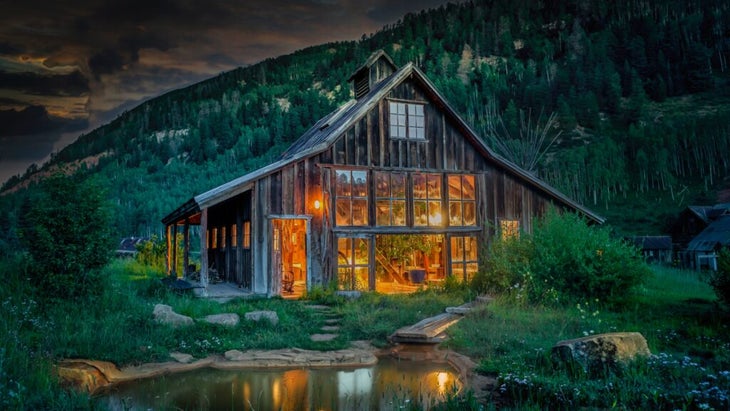 The 19th-century wooden bathhouse lit up to welcome guests with a hot-springs pool indoors and one outside.