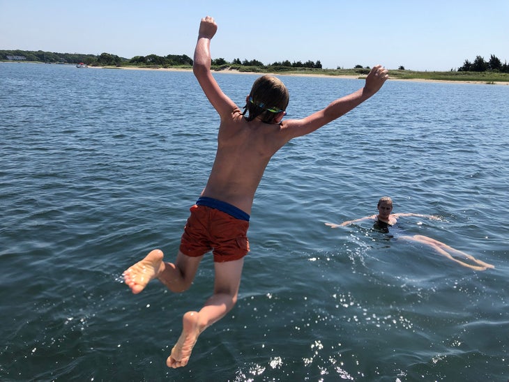 little boy jumping off a boat near cape cod Massachusetts, one of the best east coast beaches for families