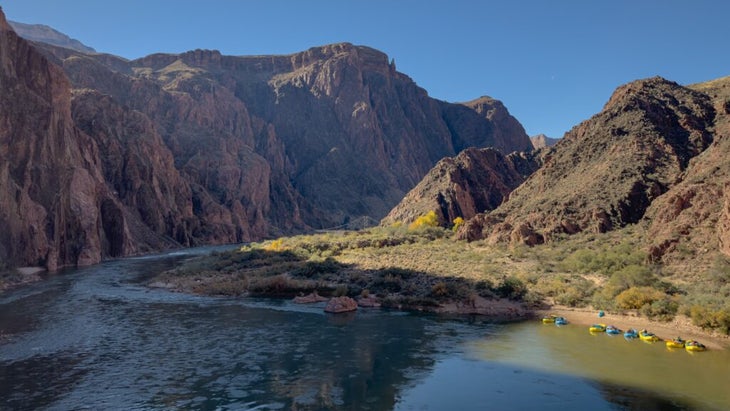 Yellow and blue inflatable rafts along the wide Colorado River have been brought ashore near Phantom Ranch. 