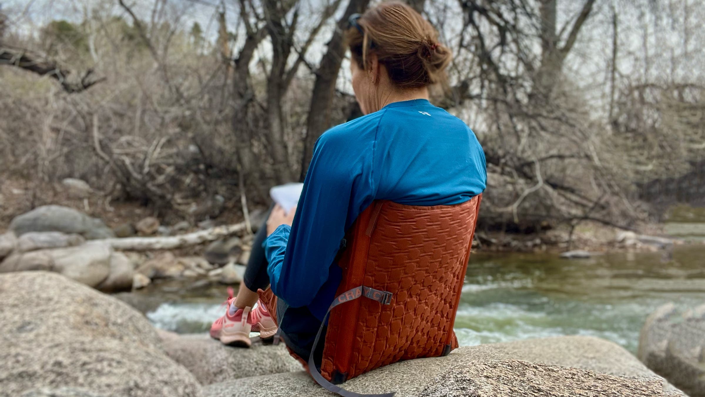 woman sitting beside stream in Crazy Creek chair