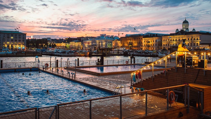 people swimming in Allas Sea Pool in Helsinki Finland at dusk