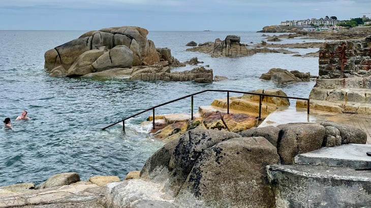 two swimmers cold plunge in the Irish Sea at Forty Foot near Dublin, Ireland