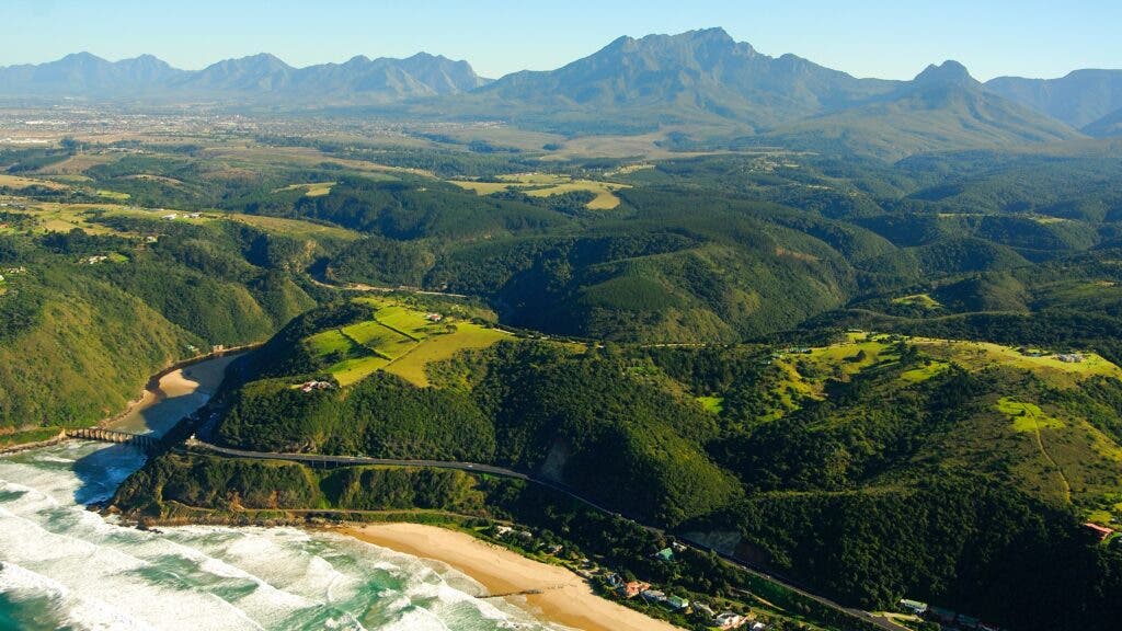 An aerial view of the South Africa’s Western Cape that takes in the Indian Ocean, Garden Route, and Outeniqua Mountains.