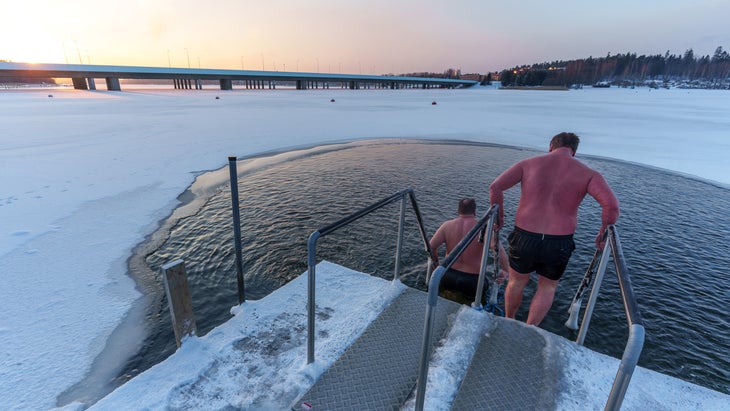 two men walking down icy steps preparing to take a cold plunge together