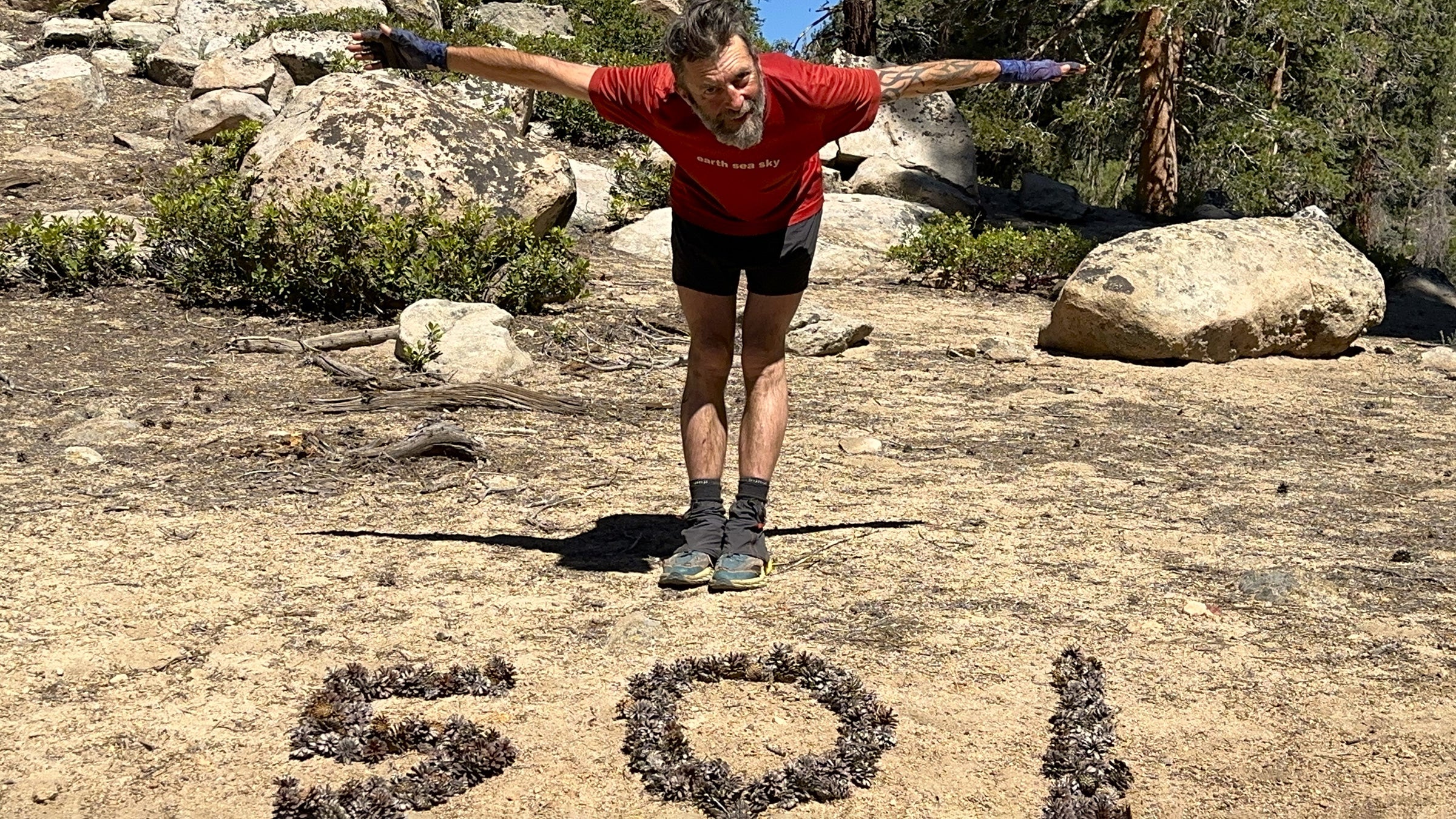 Dan Slater standing over the numbers "501" arranged with pinecones out on the trail