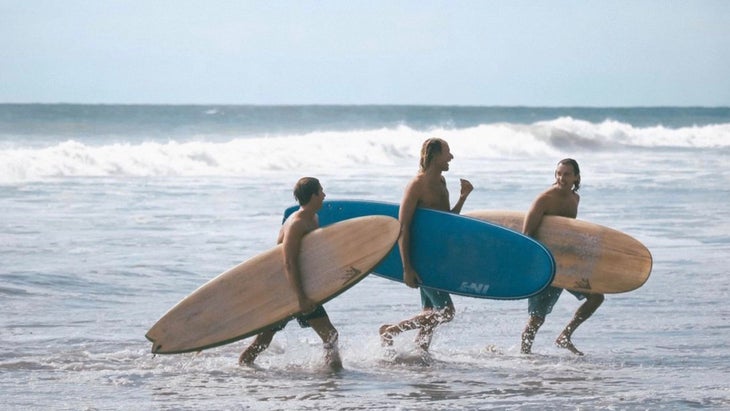 three surfers smiling as they leave the water