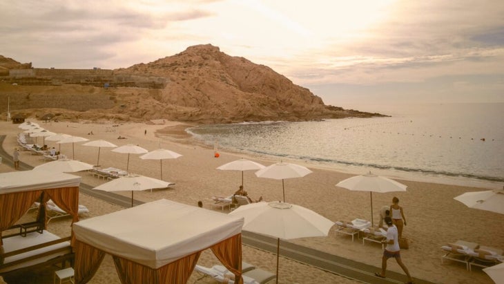 White umbrellas, lounge chairs, and cabanas line the smooth, sandy beachfront at the Montage Los Cabos.