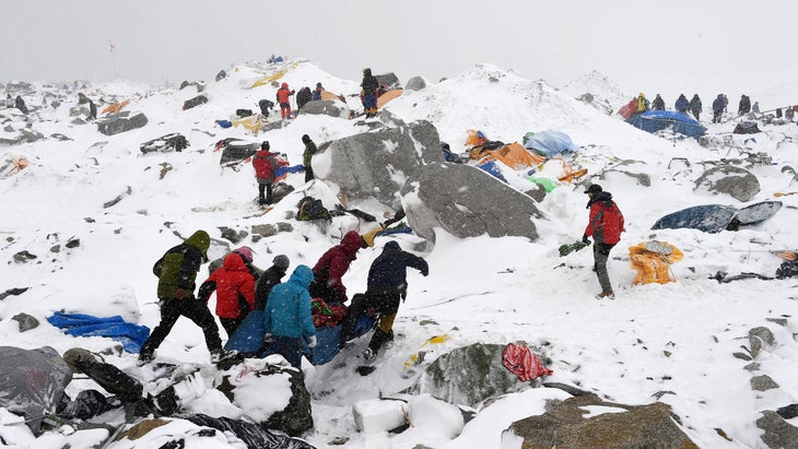 In this photograph taken on April 25, 2015, Sherpas, climbers, porters and rescue teams help carry a person injured by an avalanche that flattened part of Everest Base Camp. Rescuers in Nepal are searching frantically for survivors of a huge quake, that killed nearly 2,000, digging through rubble in the devastated capital Kathmandu and airlifting victims of an avalanche at Everest base camp.