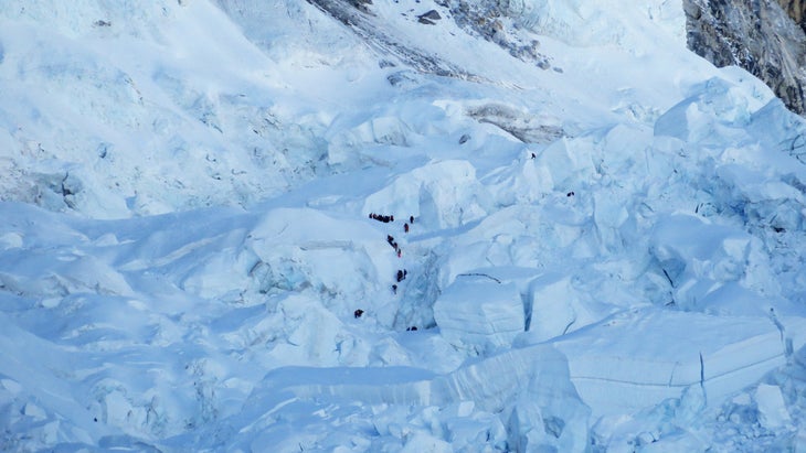 In this photograph taken on April 18, 2014, survivors (C) work to dig free and assist the injured following an avalanche that killed sixteen Nepalese sherpas in the Khumbu icefall. Immediately above them on west shoulder of Mount Everest is the glacier where the avalanche began.