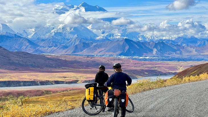 Two people on bikes gaze at Denali