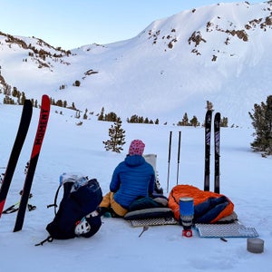 A skier rests while looking up at a ridgeline