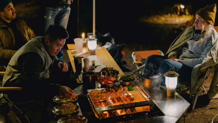 campers relaxing around a snow peak grill