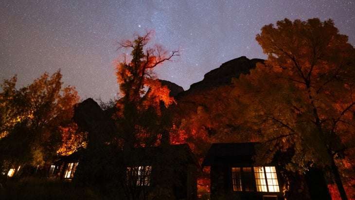 Starry skies shine brightly above the cabins and trees on the Grand Canyon floor.